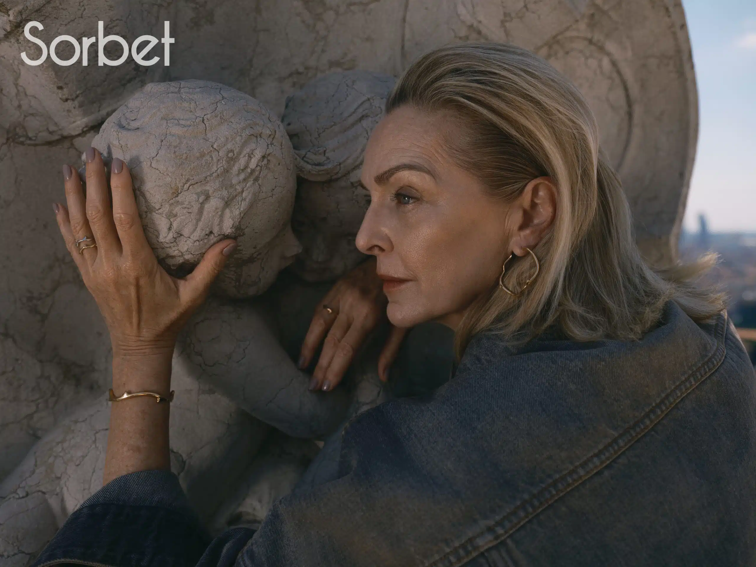 woman leaning against a statue in Milan wearing Dior jewelry and Dior clothes