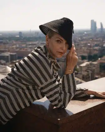woman laying over a balcony with the Milanese skyline is a backdrop wearing Dior jewelry and Dior fashion