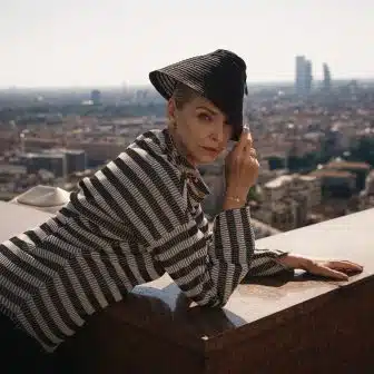 woman laying over a balcony with the Milanese skyline is a backdrop wearing Dior jewelry and Dior fashion