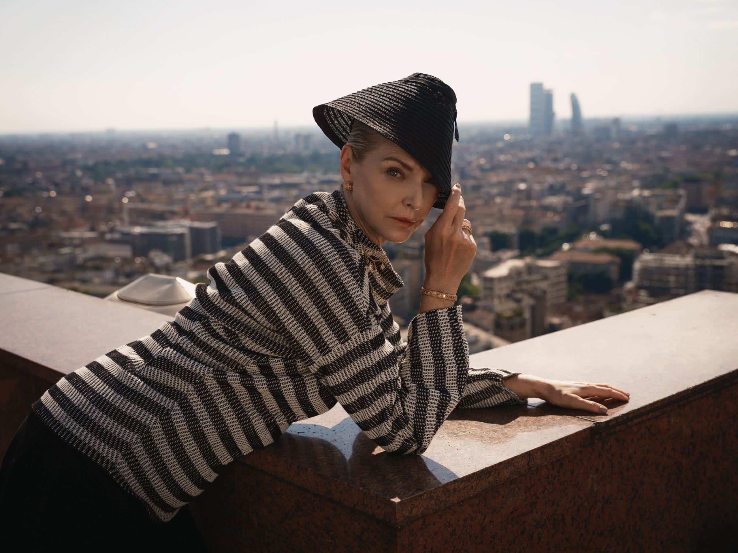 woman laying over a balcony with the Milanese skyline is a backdrop wearing Dior jewelry and Dior fashion