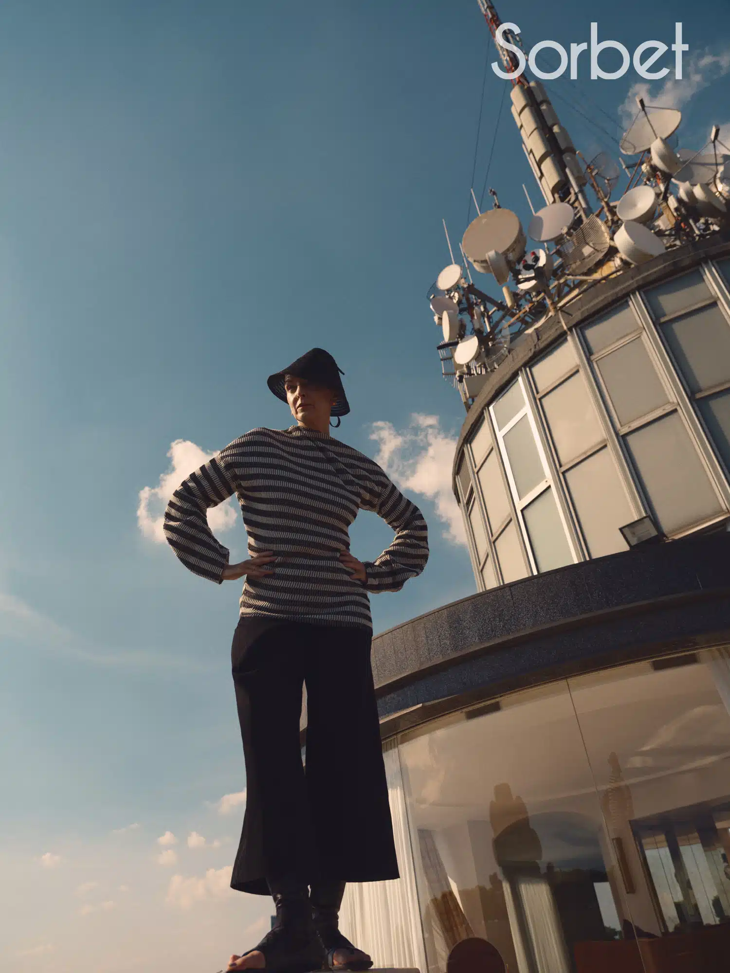 woman laying over a balcony with the Milanese skyline is a backdrop wearing Dior jewelry and Dior fashion