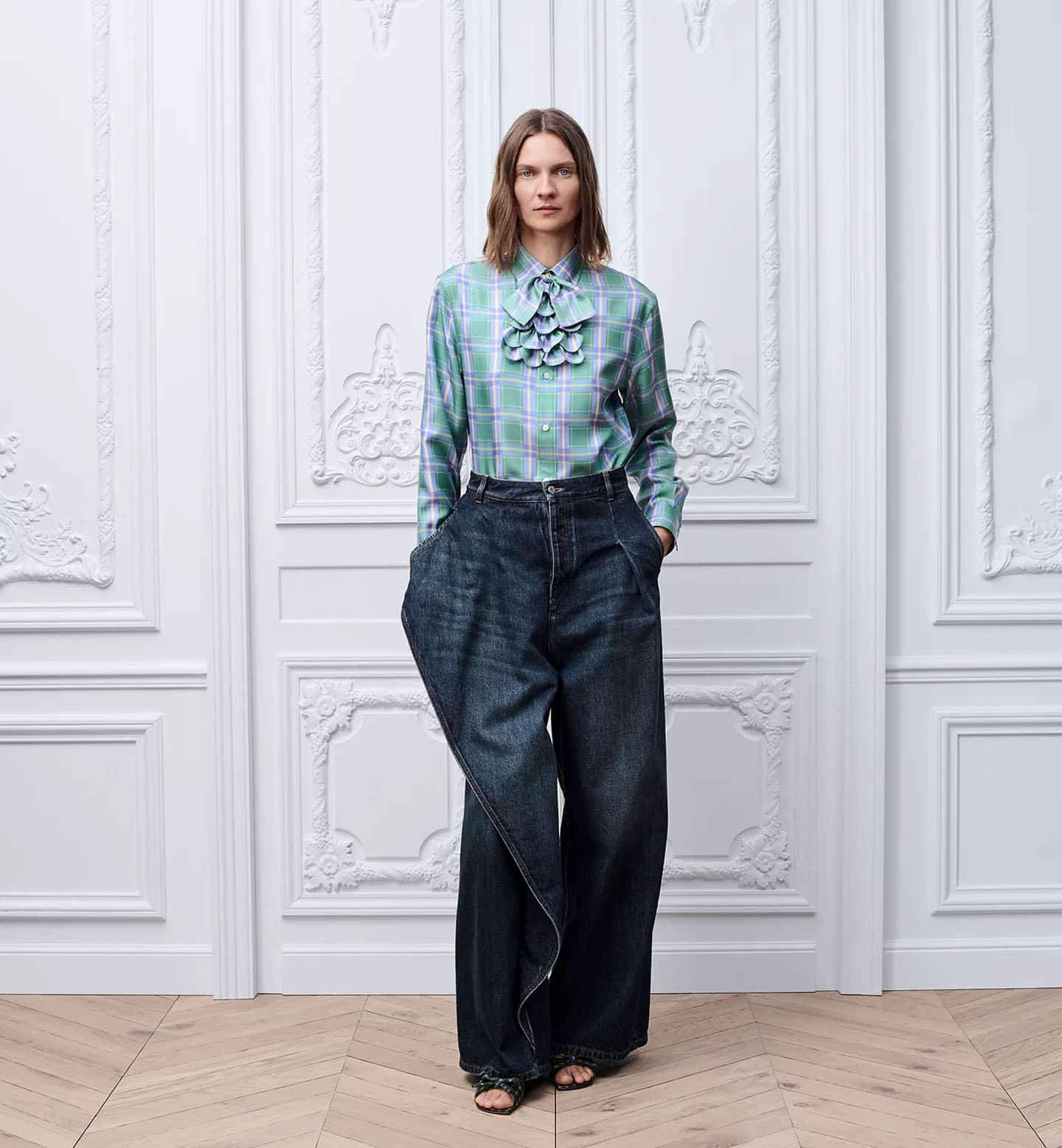 Femal model wearing Dior spring summer 2026 by Jonathan Anderson Draped Flared Jeans in blue with a checkered button down in blue and green