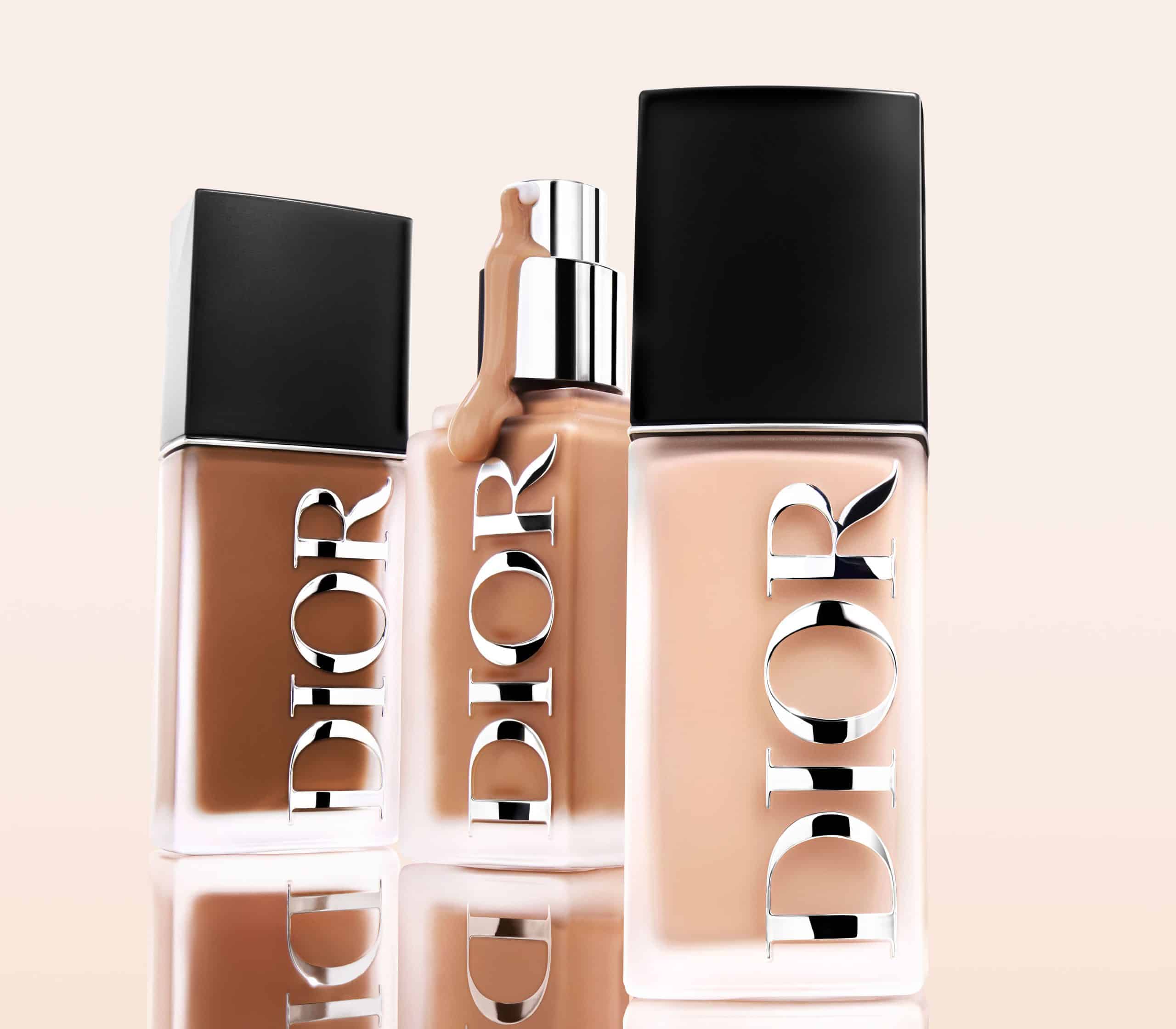 A lineup of three Dior Forever foundation bottles in various dark and light shades with reflective silver logos and black caps