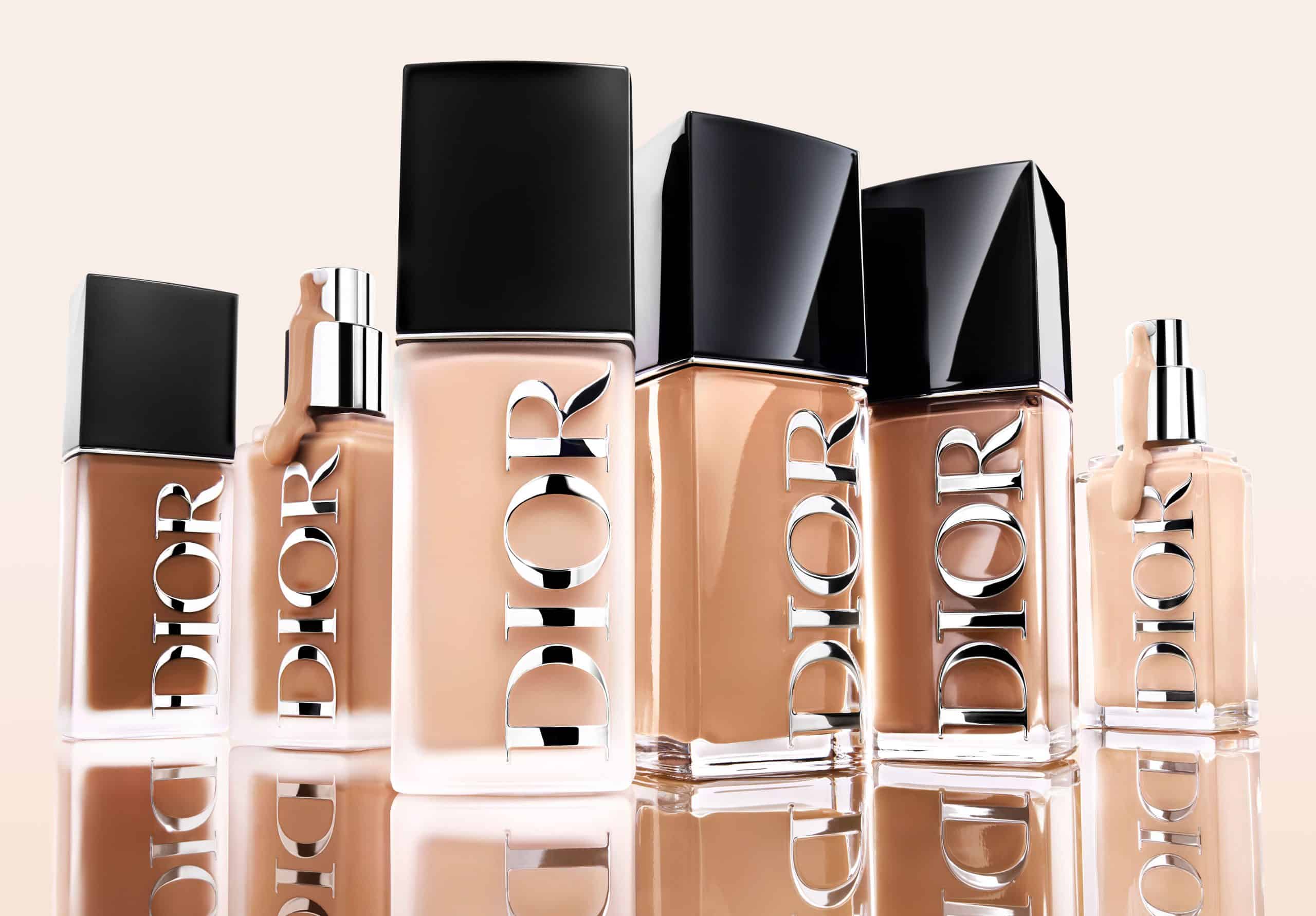 A lineup of six Dior Forever foundation bottles in various dark and light shades with reflective silver logos and black caps