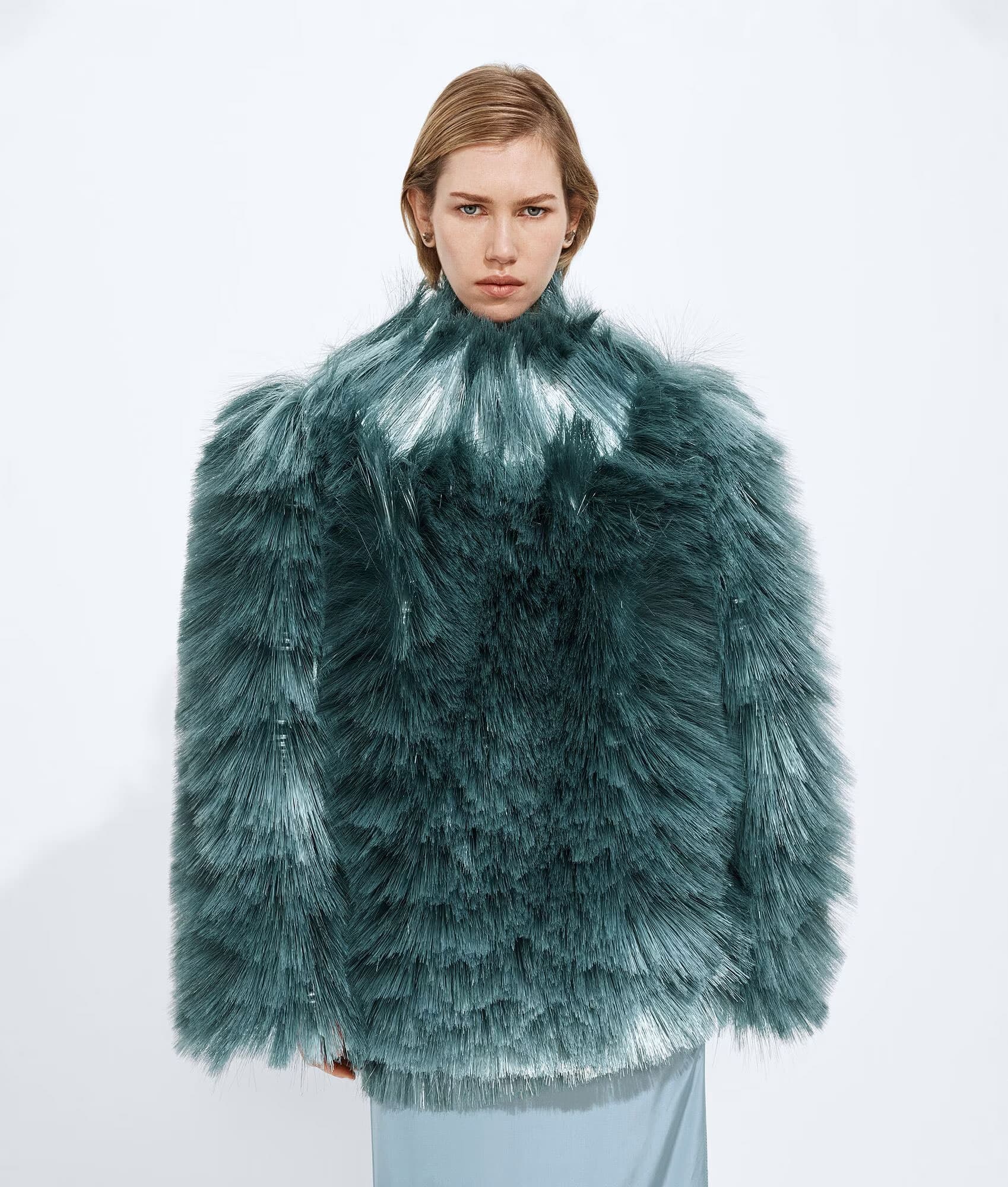 Female model wearing bottega veneta blue fringed embroidery top against a white background