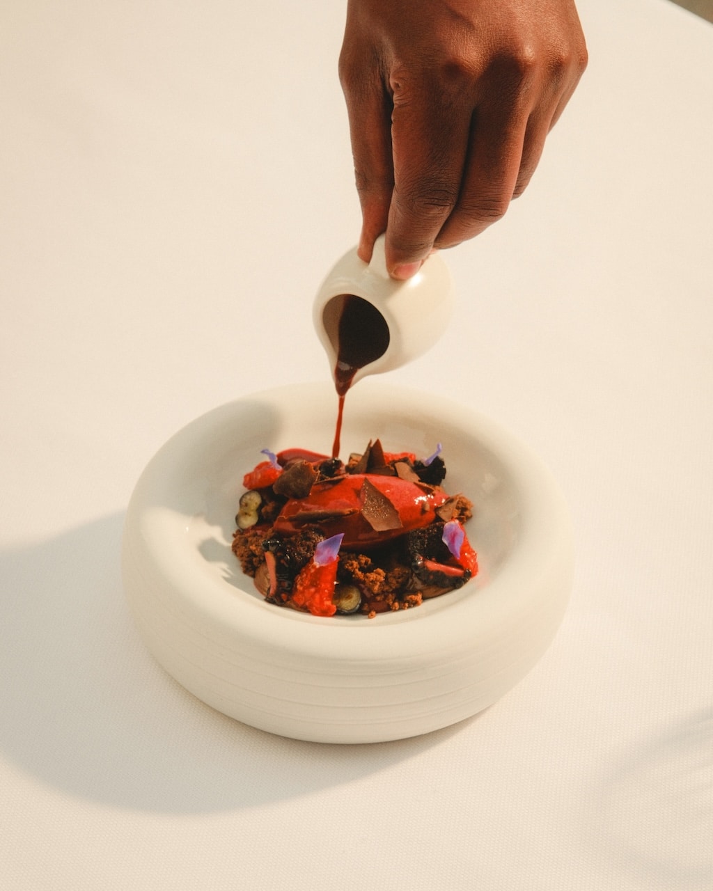 A chef pouring rich chocolate sauce over a gourmet berry and sorbet dessert at Mandarin Oriental Abu Dhabi for the Sorbet Easter 2026 Guide.