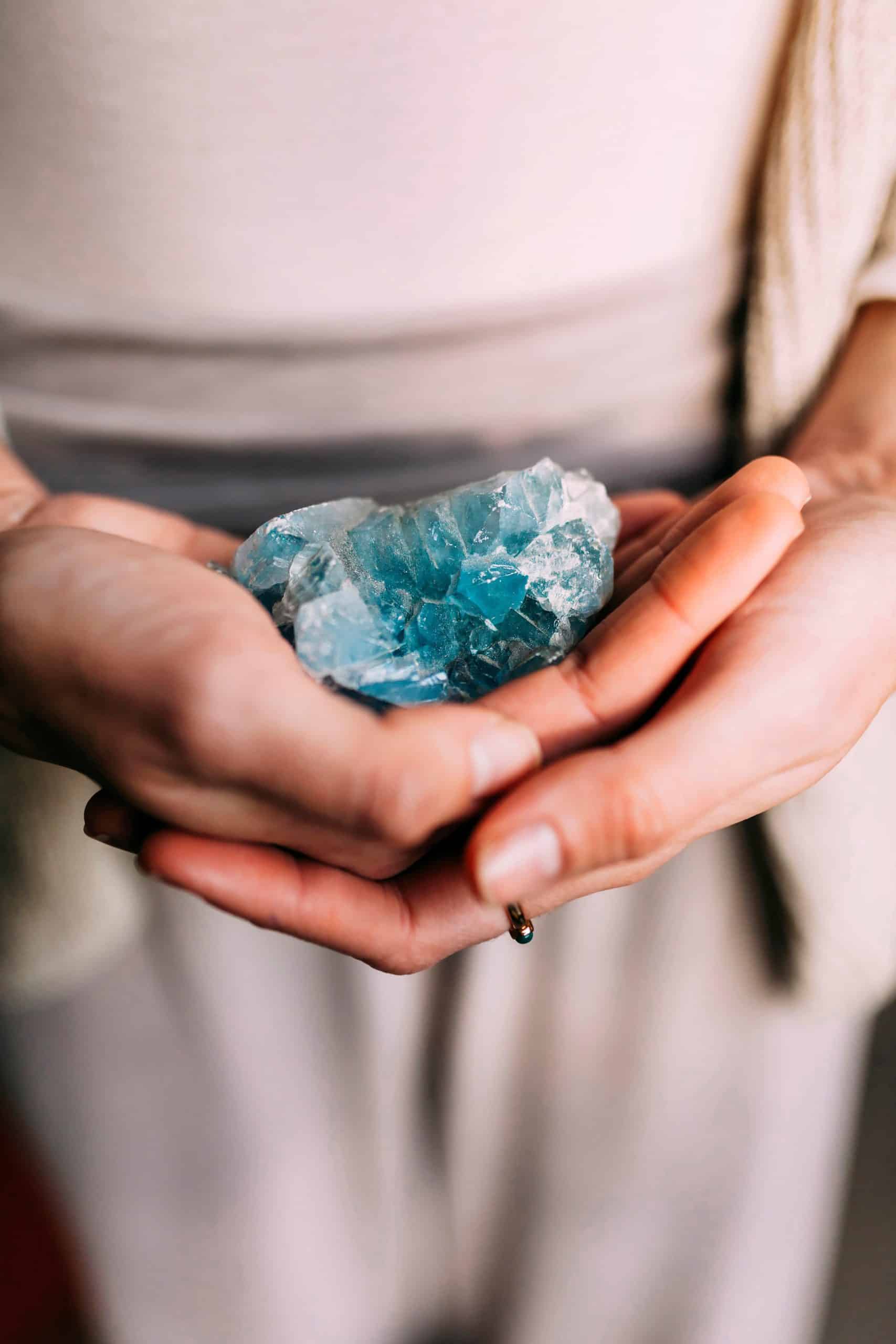 Woman holding celestine geode indoors. Spiritual unrecognizable woman with a precious mineral on her hand.