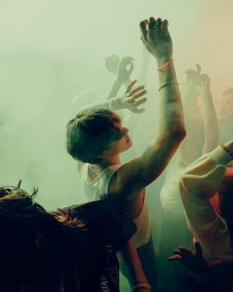 Young people dancing energetically at a vibrant music festival with colorful lighting and fog effects. Concept of concert, party, music, rhythm.