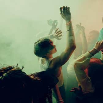 Young people dancing energetically at a vibrant music festival with colorful lighting and fog effects. Concept of concert, party, music, rhythm.