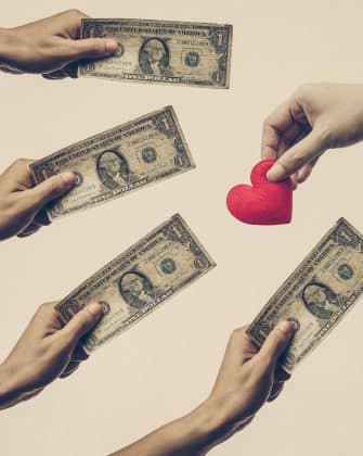 Male hand holding a dollar banknote trying to buy a red hearts from female hand - Buying love concept