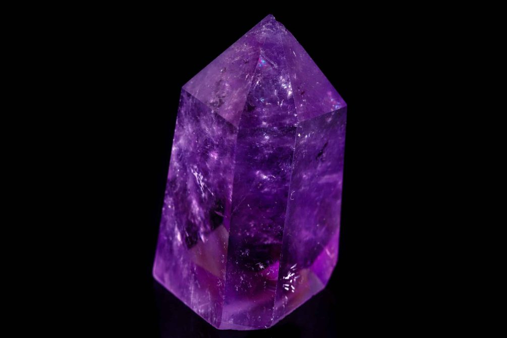 Macro mineral stone Amethyst crystal on a black background close-up